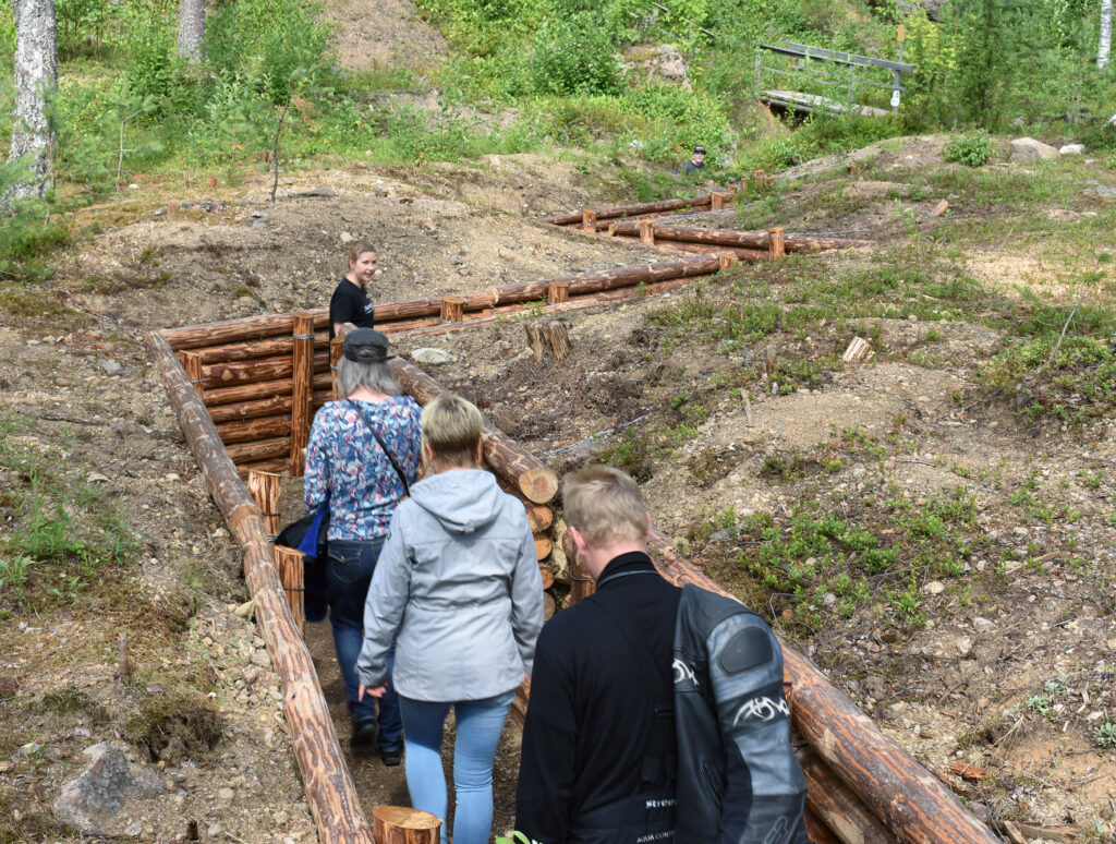 Asiakkaita kävelemässä oppaan johdolla museon yhdyshaudassa.